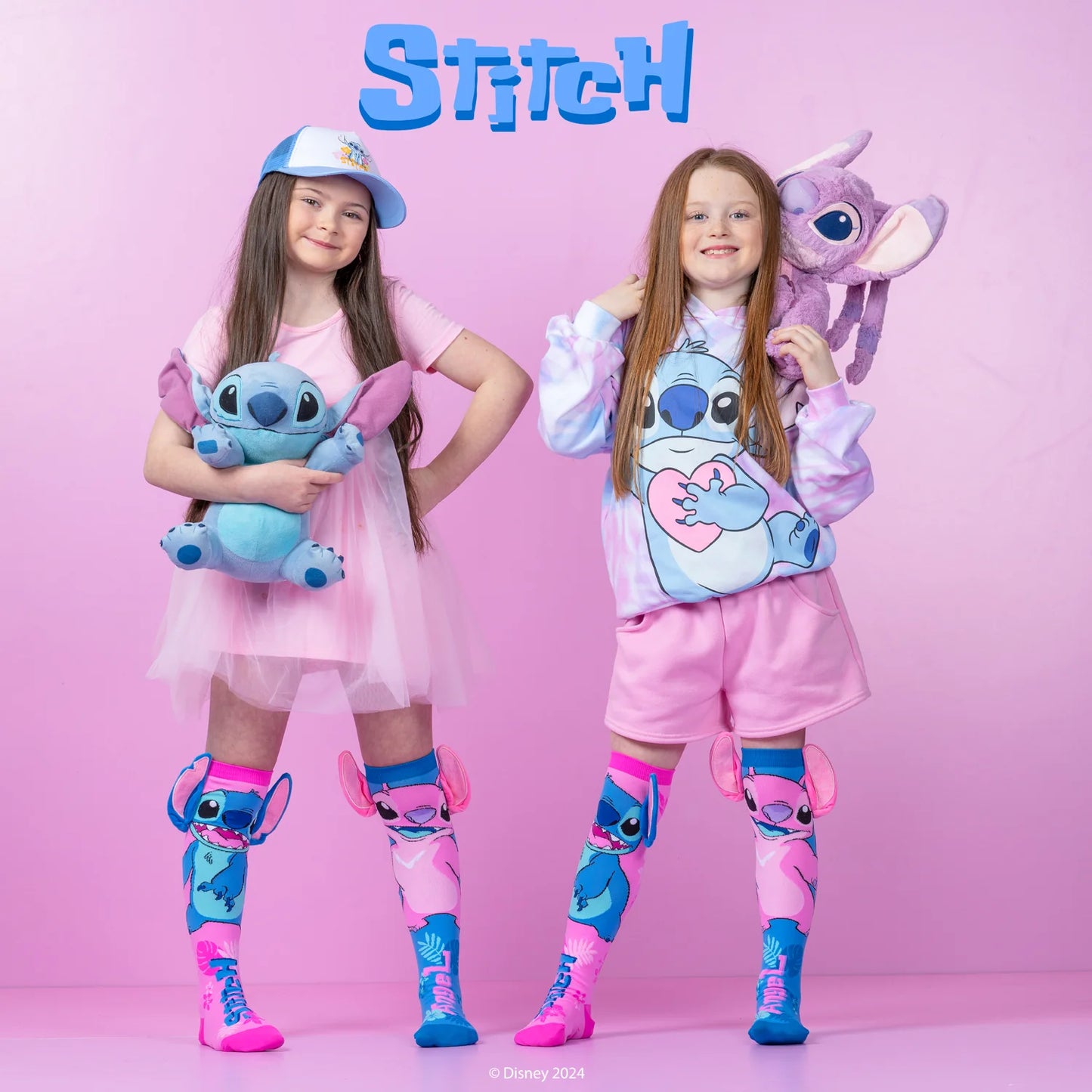 Two girls in colorful Stitch-themed outfits, wearing knee-high socks and holding plush toys against a pink background.