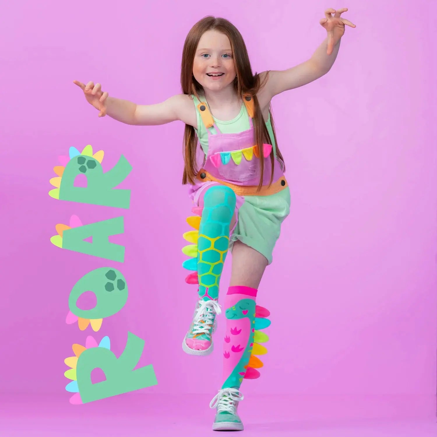 Dėvimos kojinės: vaikas mūvi dinozaurų kojines, “ROAR” užrašas ir dinozaurų motyvai matomi realiai