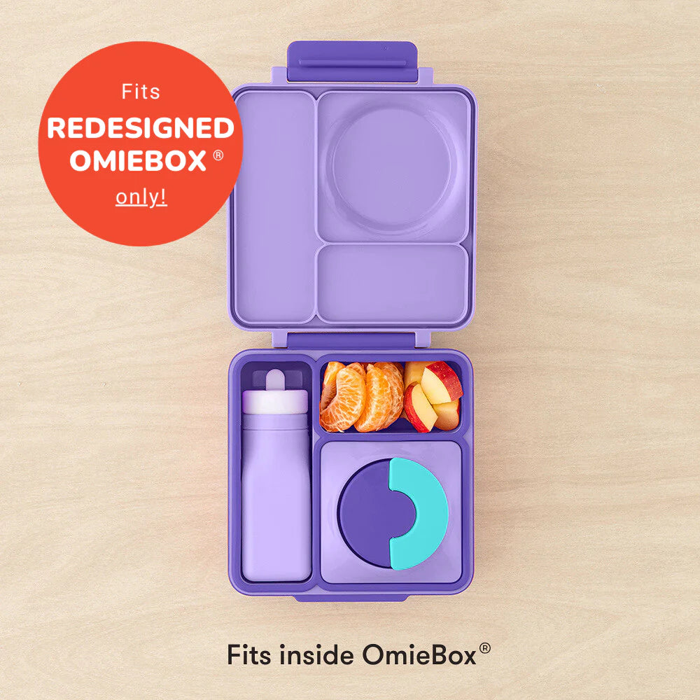 Violetinė OmieBox pietų dėžutė su skyreliais, kurioje telpa mėlynas silikoninis buteliukas, vaisiai ir apvalus indelis su dangteliu.