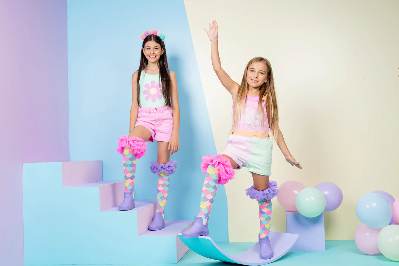 Stambiu planu pavaizduoti blizgūs tiulio raukiniai viršuje, primenantys undinėlės pelekus; Dėvimos kojinės: mergaitė mūvi MERMAID FRILLS kojines – pastelinis blizgesys ir tiulio papuošimai išryškėja dėvint.