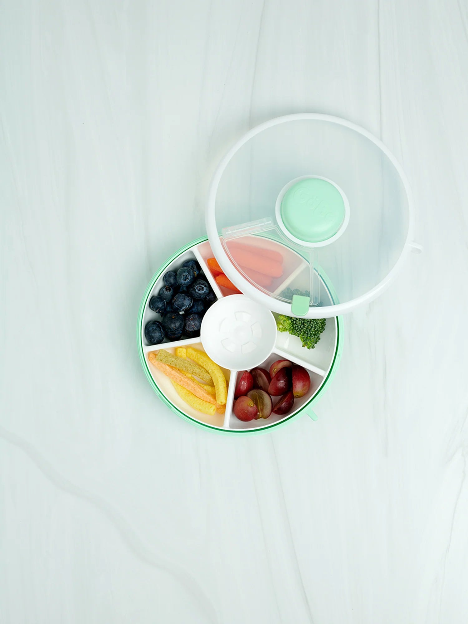 GoBe Snack Spinner lunchbox for kids featuring divided sections with fresh fruits and a dip container, in green color.