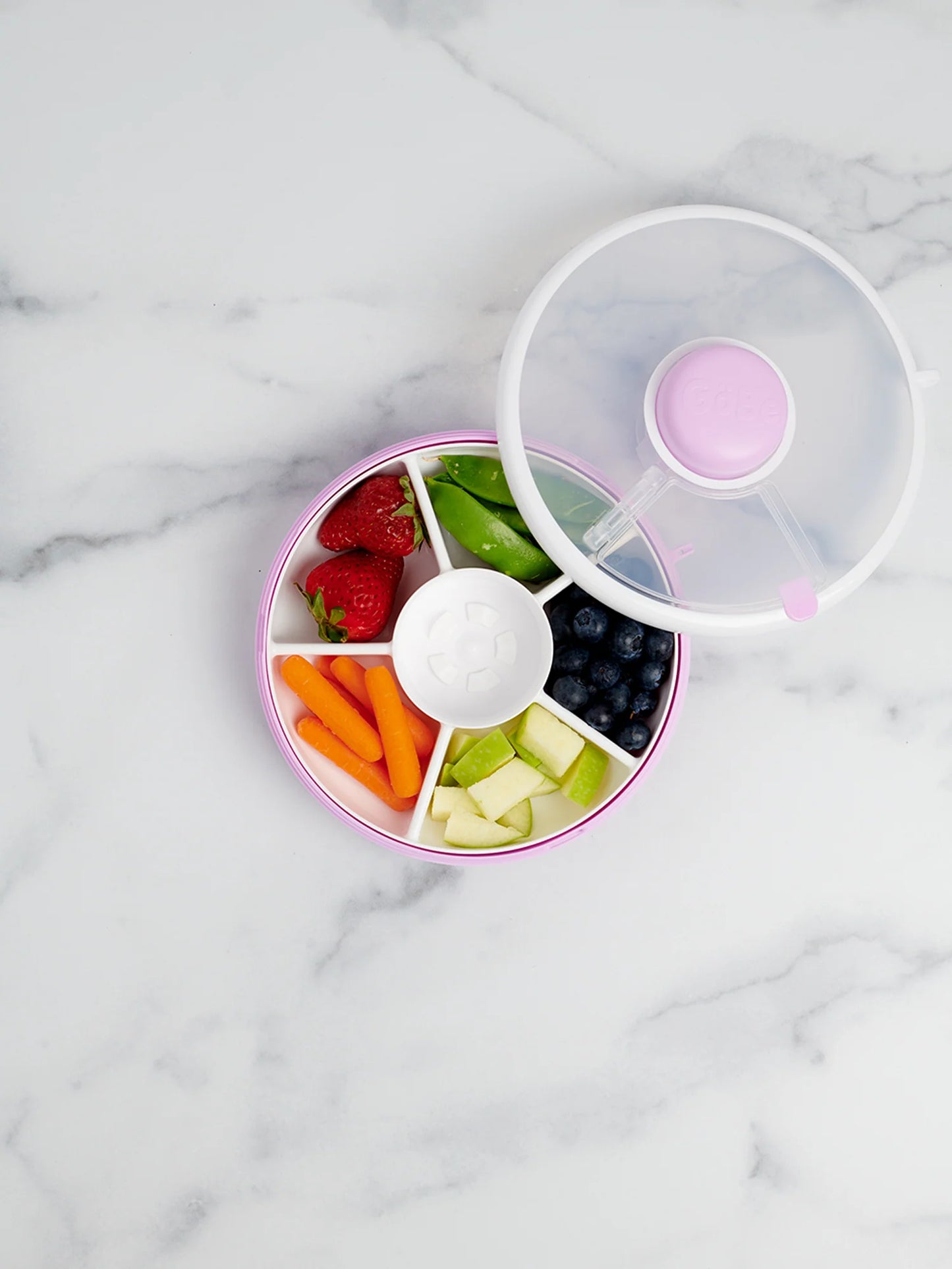 GoBe Snack Spinner in lilac with assorted fruits and veggies, including strawberries, blueberries, carrots, and apples.
